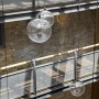 Residential apartment building atrium - Wapping High Street | Close-up of chandelier pendants, restored timber rail and steel mesh frames | Interior Designers